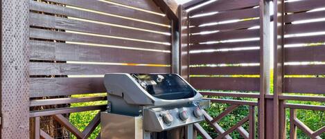 A barbecue grill with a digital display, set against a wooden fence with a lattice design.