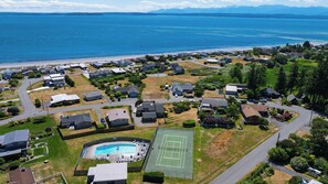 Vista aerea di un quartiere residenziale con case, un campo da tennis e una piscina.