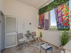 A balcony with a table, chairs, a potted plant, and a view of the sea. - Two Bedroom Apartment with Terrace and Sea View (Omis)