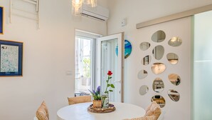 Ein Essbereich mit einem runden Tisch, weißen Stühlen, einer Vase mit Blumen und einer Wand mit runden Spiegeln.