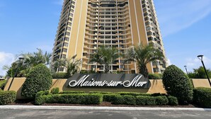 A tall hotel with a sign reading 'Maisons-sur-Mer' surrounded by well-maintained landscaping. - 22nd-Floor Oceanfront Luxury · Maisons Sur-Mer (Myrtle Beach)