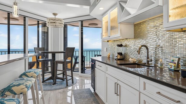 A modern kitchen with a large island, a dining area with a view, and a balcony with a view. - 22nd-Floor Oceanfront Luxury · Maisons Sur-Mer (Myrtle Beach)