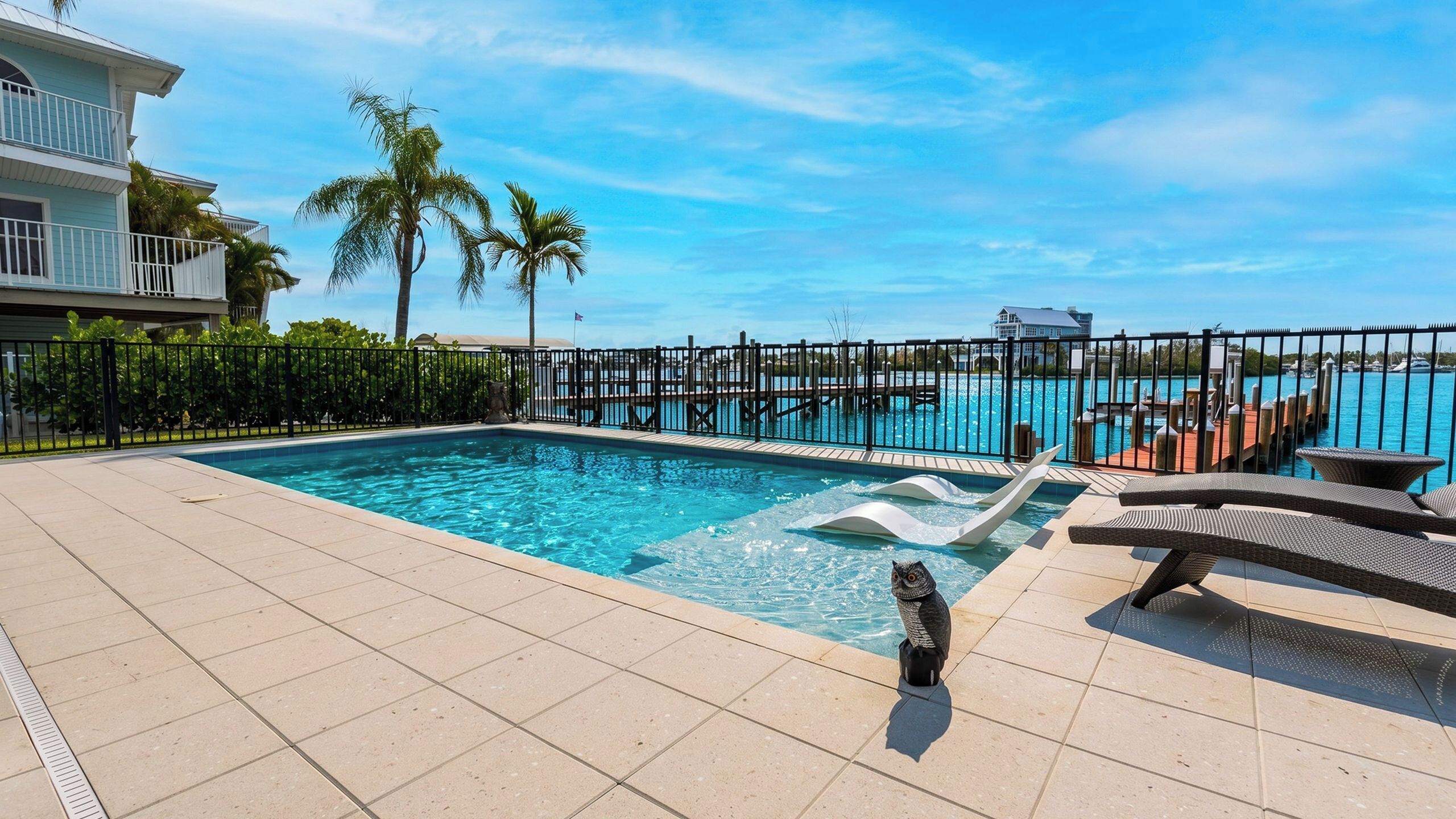 A swimming pool with a water slide, lounge chairs, and a view of the ocean.