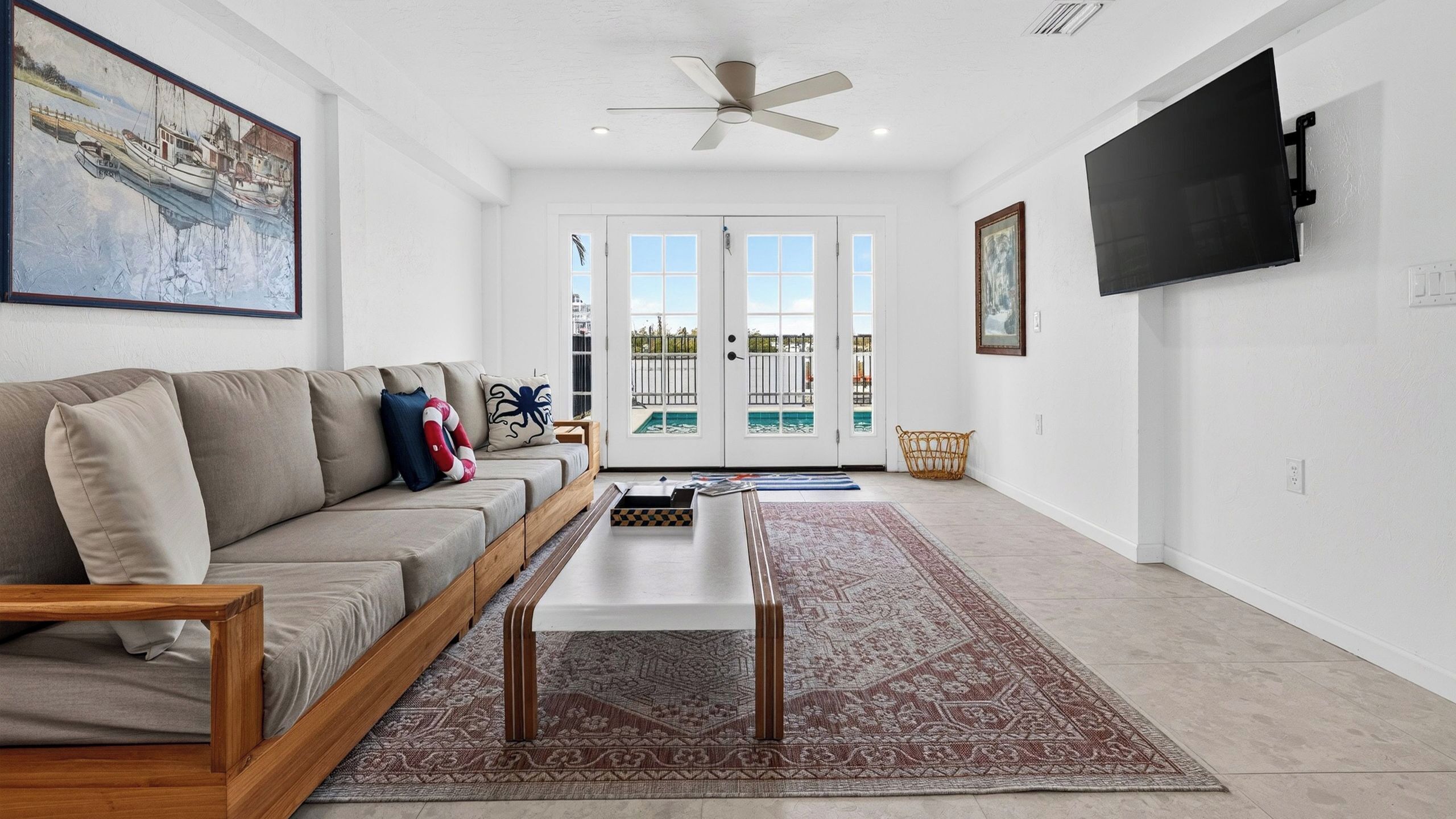 A living room with a sofa, coffee table, and a view of a pool through glass doors.