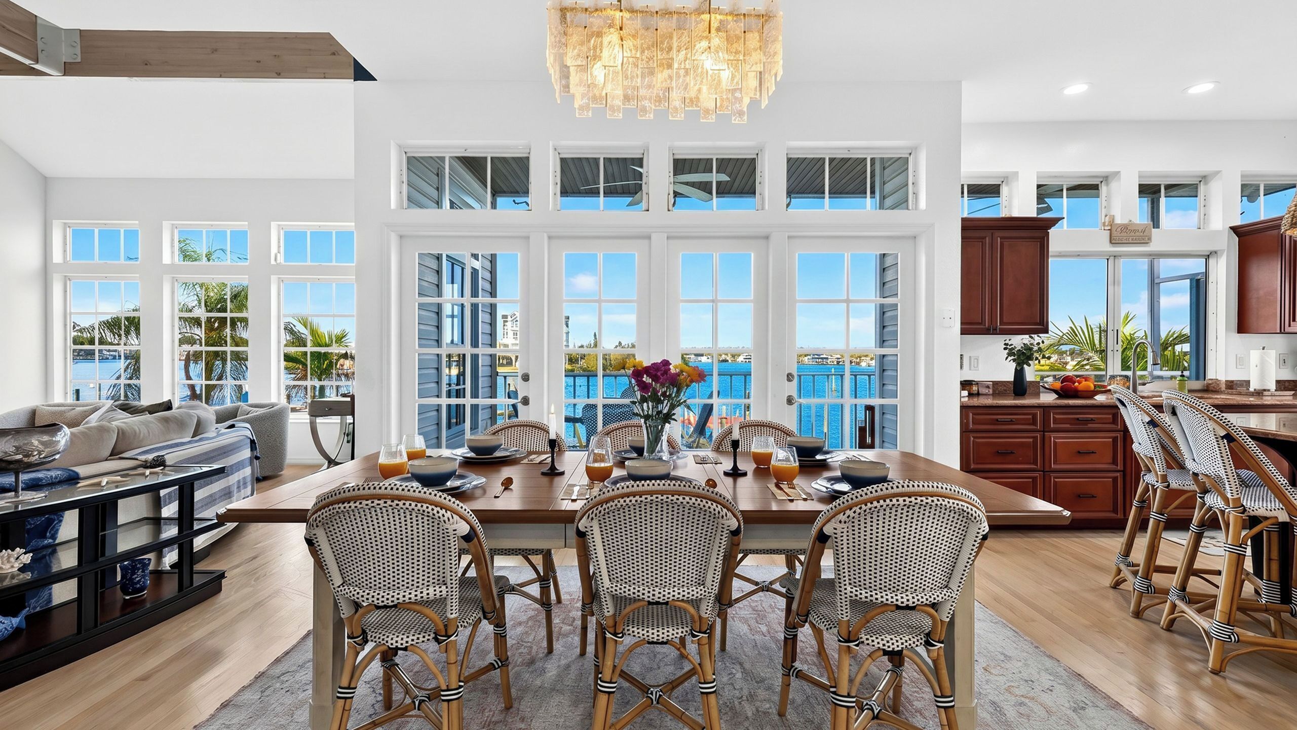 A spacious dining area with a view of the sea, large windows, and a modern chandelier.