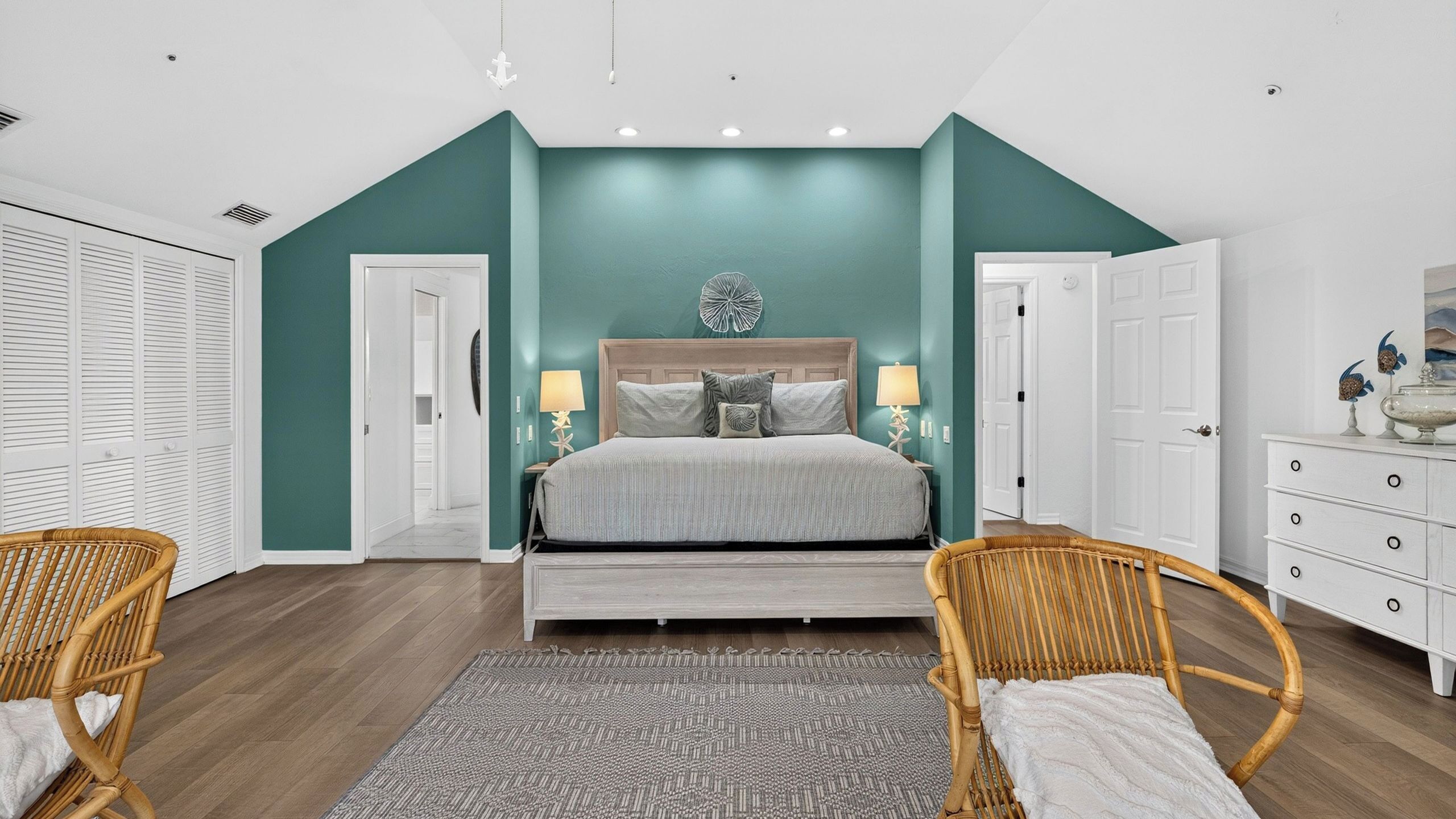 A bedroom with a bed, two bedside tables with lamps, a large window, and a wardrobe.
