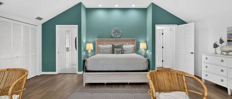 A bedroom with a bed, two bedside tables with lamps, a large window, and a wardrobe.