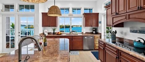 Una cocina moderna con una isla grande, electrodomésticos de acero inoxidable y vista al agua.