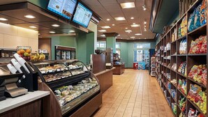 Un comptoir de produits alimentaires proposant une variété d’articles, une vitrine réfrigérée et une étagère pour les collations.
