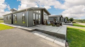 Uma casa moderna com um pátio, janelas amplas e vista para o campo.