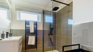 Um banheiro moderno com chuveiro de vidro, um porta-toalhas e uma pia.