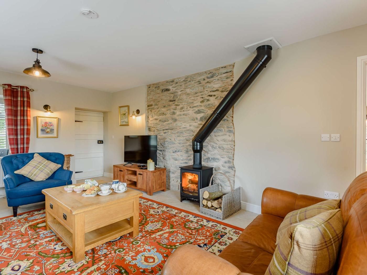 A living room with a stone wall, a fireplace, a television, and a blue sofa.