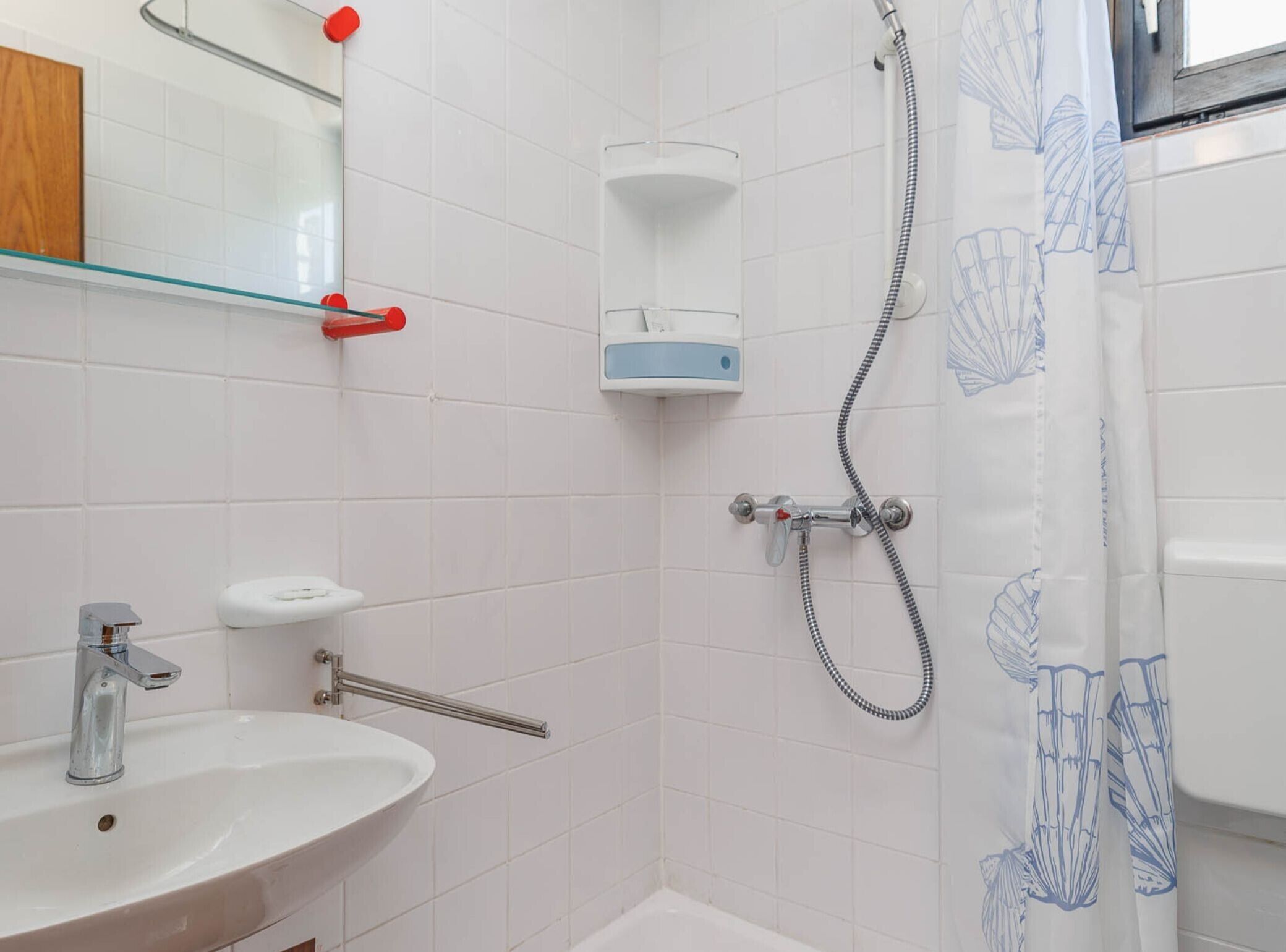 A bathroom with a sink, mirror, shower, and a towel rack.