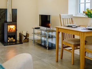 Ein modernes Wohnzimmer mit Kamin, einem Glastisch, einem Holzespeisetisch und einem Fernseher.