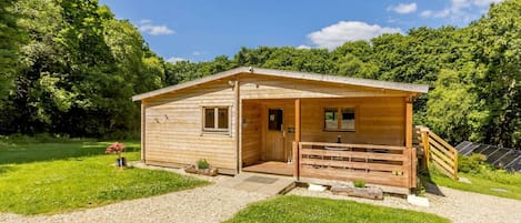 A wooden cabin with a porch, a small window, and a door.