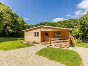 A wooden cabin with a porch, a small window, and a door. - 2 Bed in Holsworthy (oc-87765) (Whitstone)