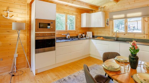 Una cabaña de madera con cocina, comedor y un ventanal grande.