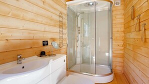 Baño de cabaña de madera con ducha, lavabo e inodoro.