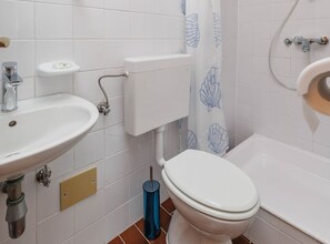 Ett badrum med ett vitt handfat, en toalett och ett badkar.