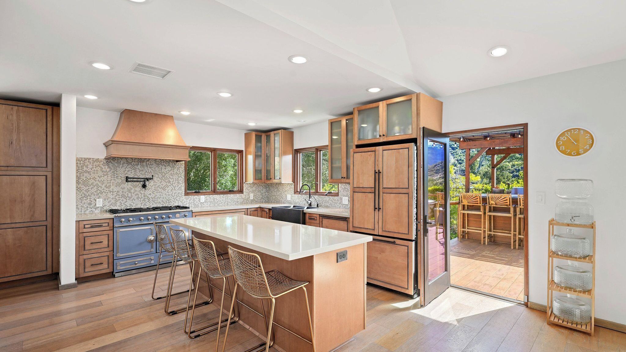A modern kitchen with wooden cabinets, a central island, and a view to an outdoor patio.