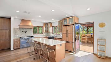 Uma cozinha moderna com armários de madeira, uma ilha central e vista para um pátio externo.