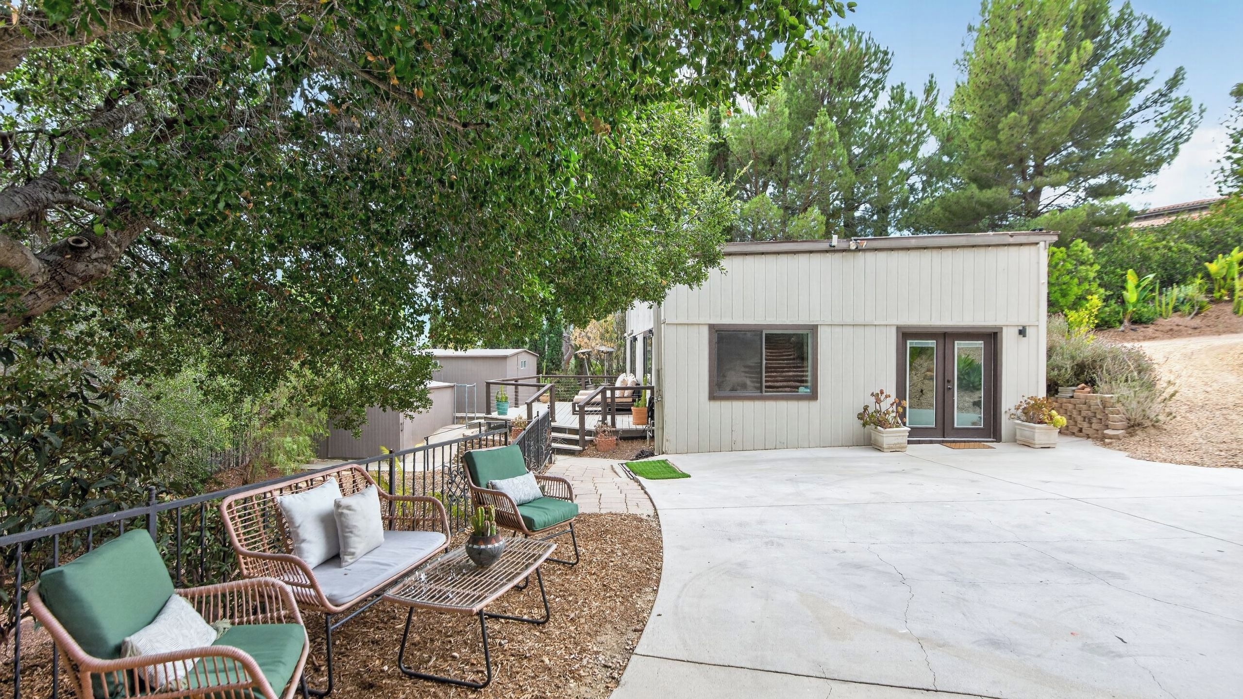 A patio with outdoor furniture, a small building, and surrounding vegetation.