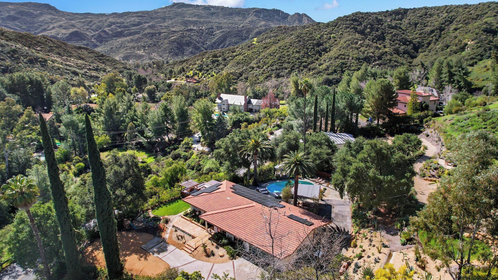 A residential area with houses, a swimming pool, and a mountainous backdrop.