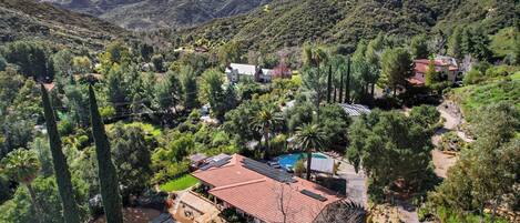 A residential area with houses, a swimming pool, and a mountainous backdrop.