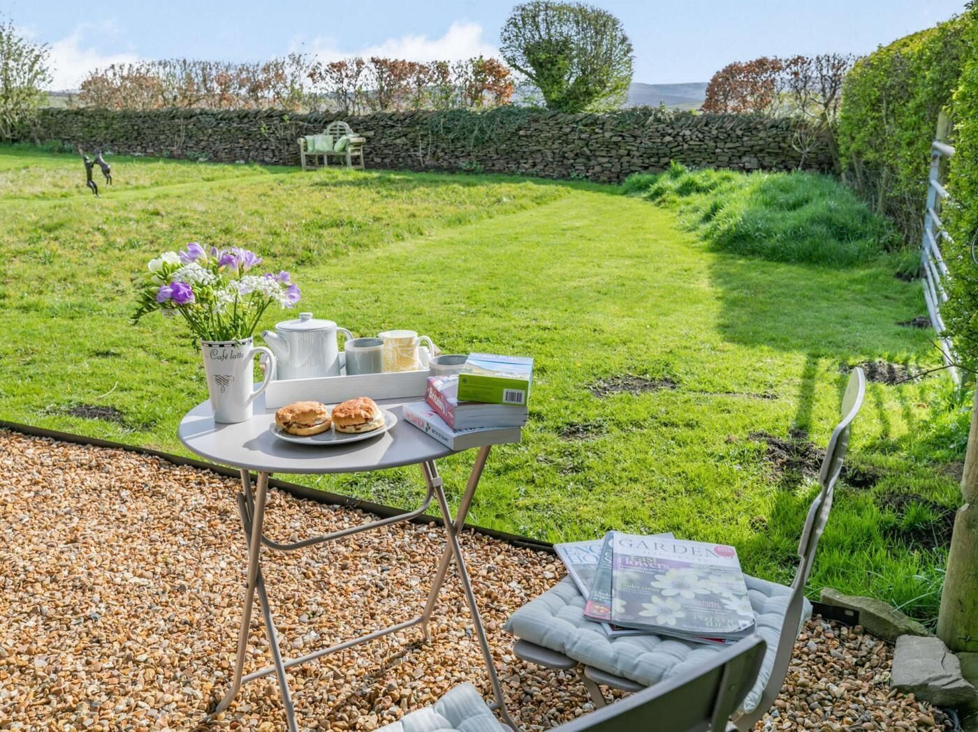 A patio with a table set for a meal, a vase of flowers, and a magazine.