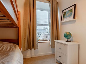 Ein Schlafzimmer mit Etagenbett, einem Fenster mit Vorhängen, einem Globus auf einem Nachttisch und einer gerahmten Karte an der Wand.