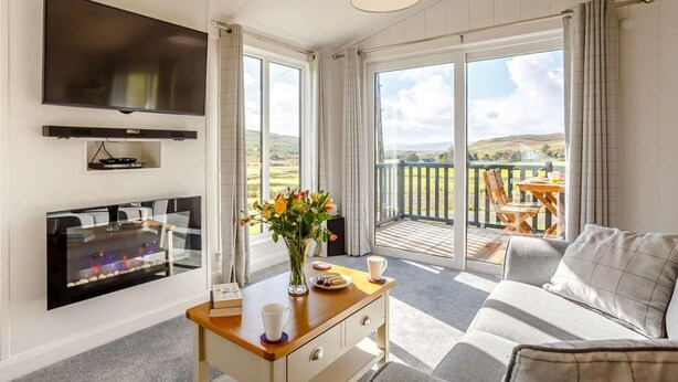 Un salon moderne doté d’un téléviseur à écran plat, d’une cheminée, d’un coin repas et d’un balcon offrant une vue sur la campagne.