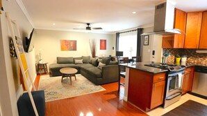 A modern kitchen with a central island, a dining area with a table and chairs, and a living room with a sofa and a small round table. - Quiet PB Retreat w/ Cal KING Bed, AC & Parking (San Diego)