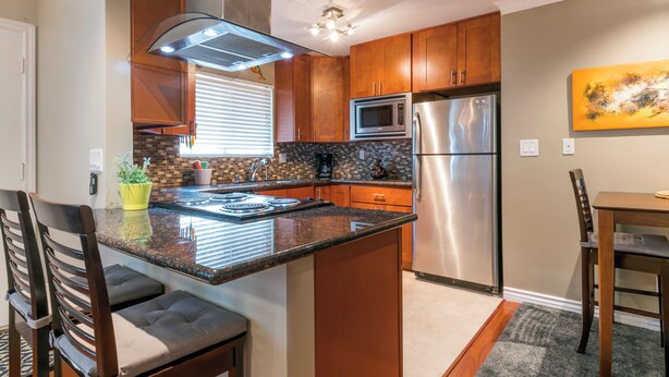 A kitchen with wooden cabinets, a stainless steel refrigerator, a microwave, and a stove. - Quiet PB Retreat w/ Cal KING Bed, AC & Parking (San Diego)
