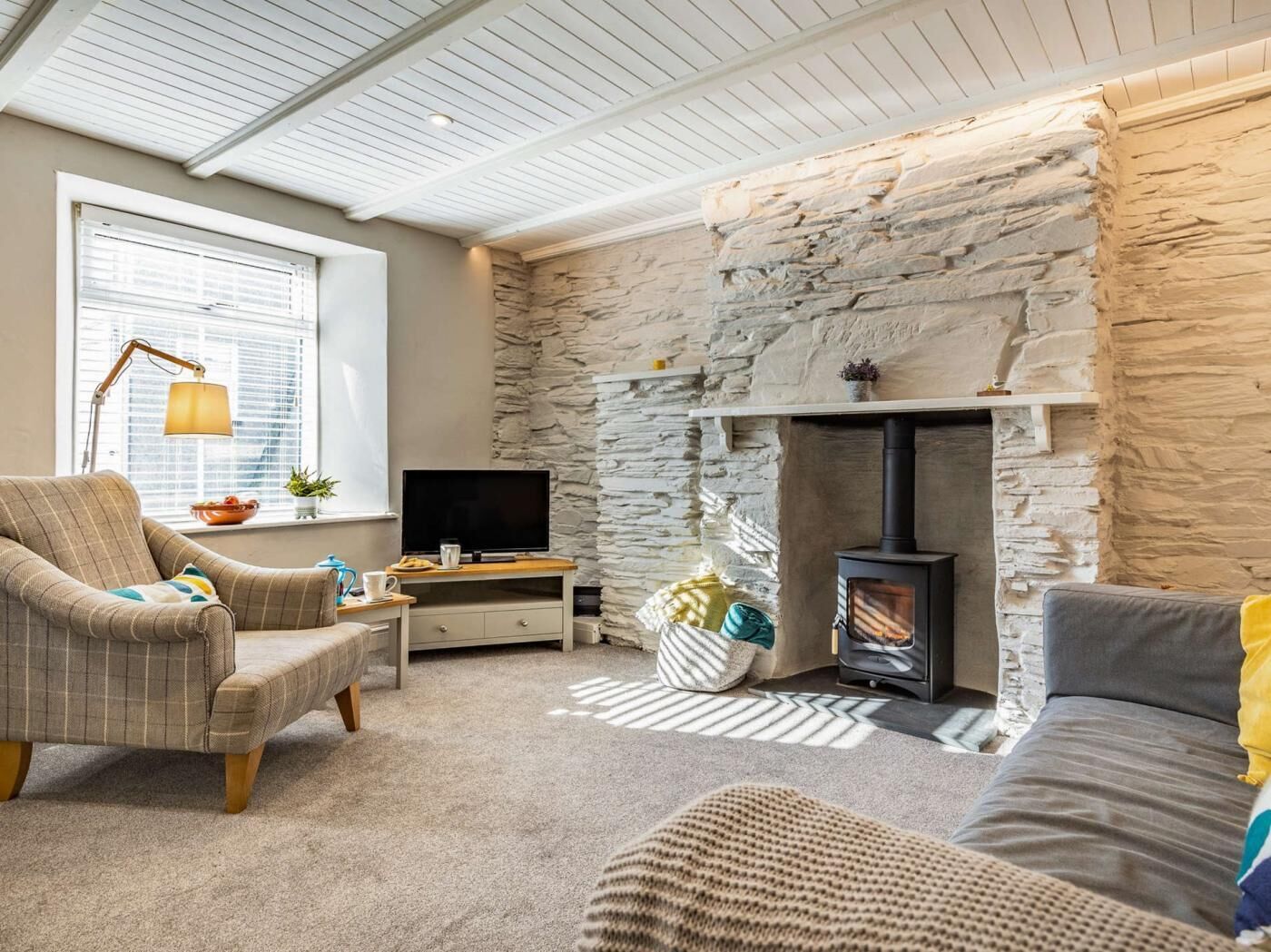 A cozy living room with a stone wall, a fireplace, a television, and a comfortable seating area.