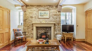 A cozy living room with a stone fireplace, wooden furniture, and a television. - 1 Bed in Crieff (oc-87497) (Crieff)
