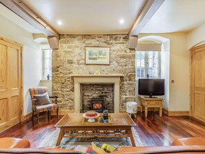 A cozy living room with a stone fireplace, wooden furniture, and a television. - 1 Bed in Crieff (oc-87497) (Crieff)