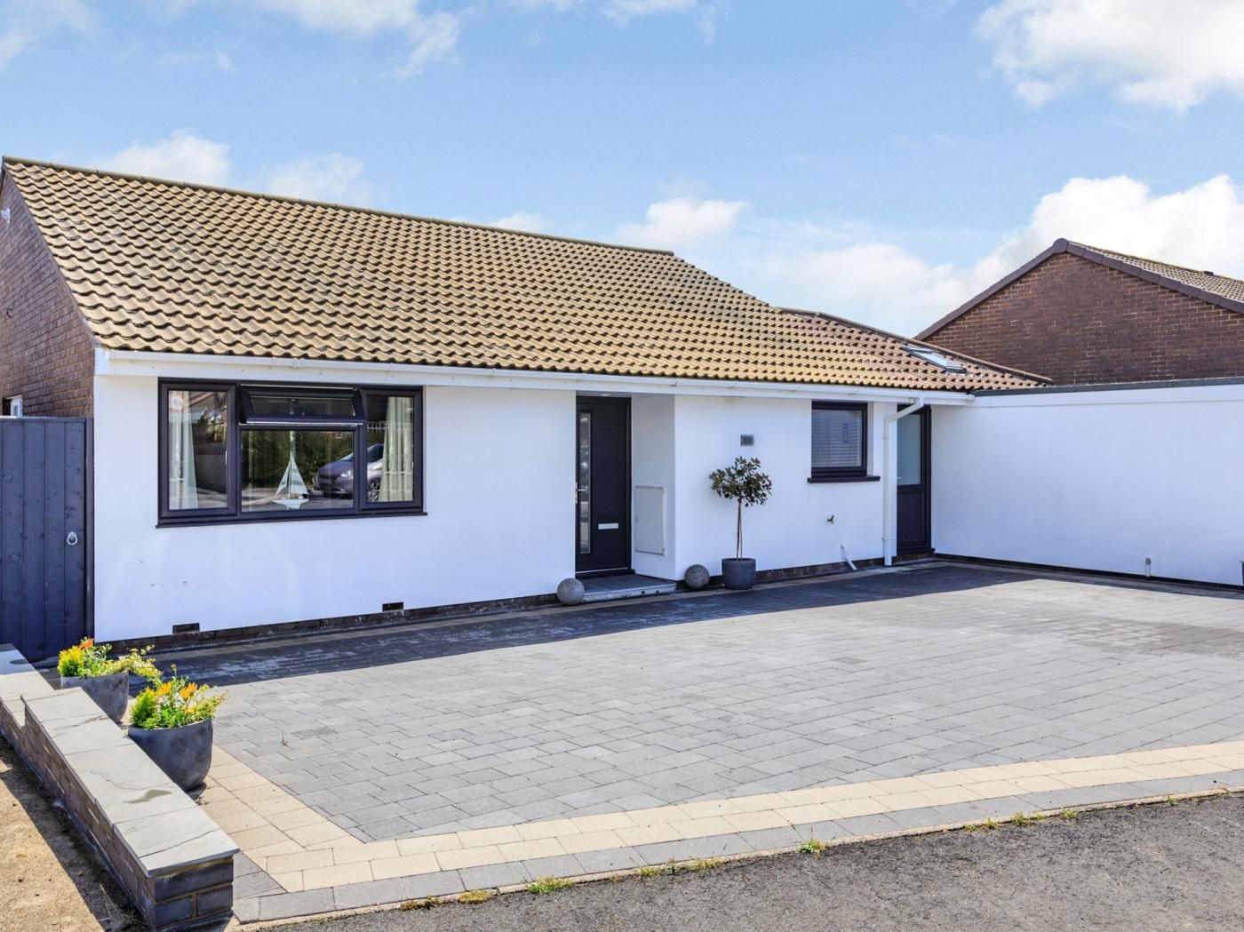 A modern two-story house with a tiled roof, a front door, and a paved driveway.