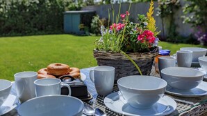 Ein Tisch im Freien mit einer Blumenkorb, einer Kamera und einem Teller Donuts.