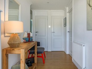 Ein Flur mit einem Holztischchen, einer Lampe, einem Stuhl und zwei weißen Türen.