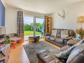 Ein Wohnzimmer mit Sofa, Hocker und Bücherregal.
