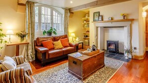 Ein gemütliches Wohnzimmer mit Ledersofa, Couchtisch aus Holz, Kamin und Bücherregal.