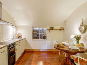 A kitchen with a stove, oven, and sink; a dining table with breakfast items; a window with a view; and a shelf with jars. - 1 Bed in Crieff (oc-87498) (Crieff)