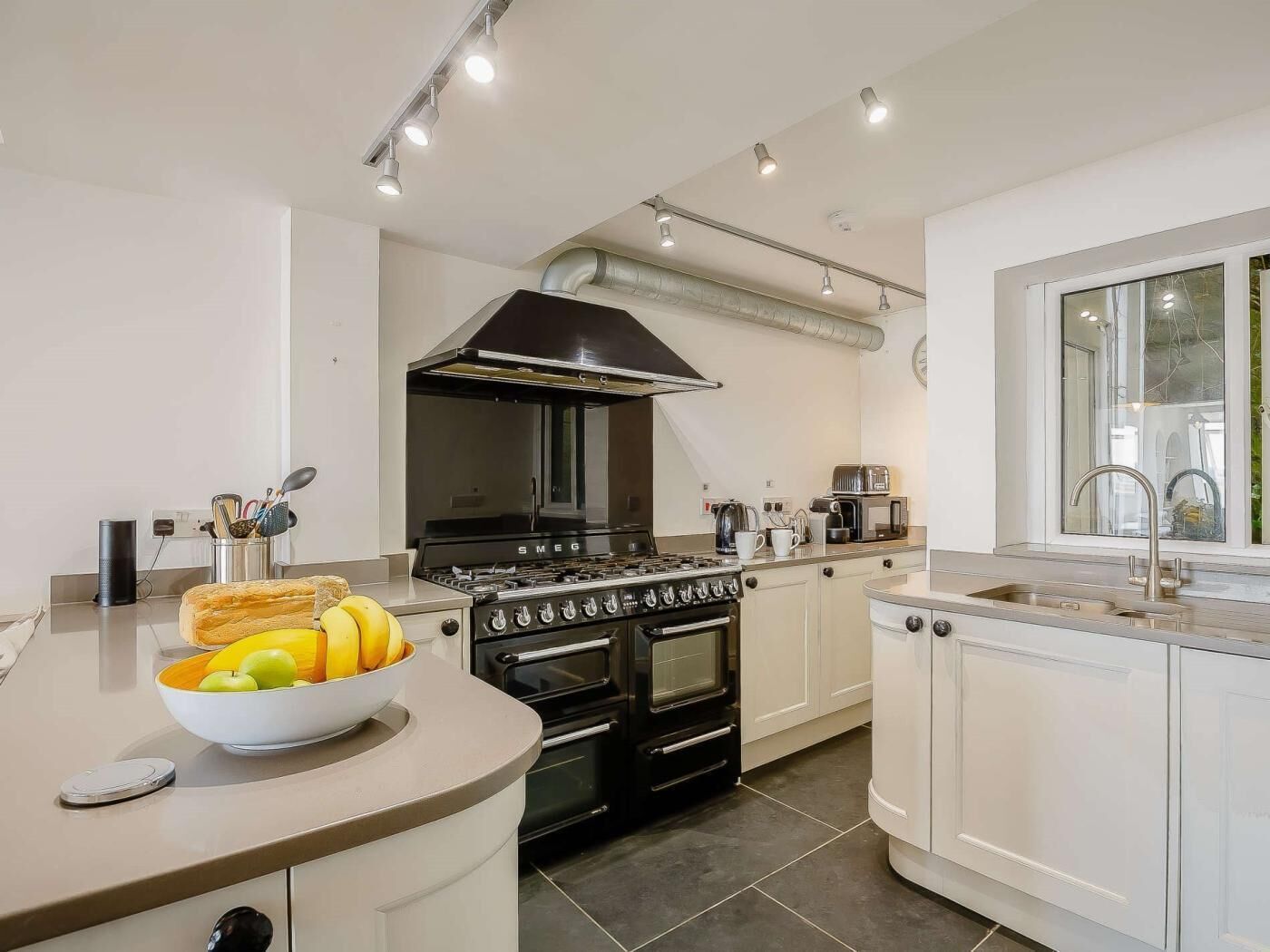 A modern kitchen with a central island, a stove, oven, and a large window.