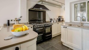 Una cocina moderna con una isla central, estufa, horno y un amplio ventanal.