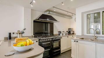 A modern kitchen with a central island, a stove, oven, and a large window.