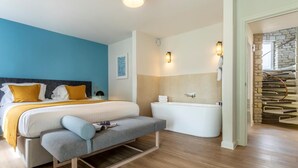 A modern hotel room with a bed, bench, bathtub, and a spiral staircase.