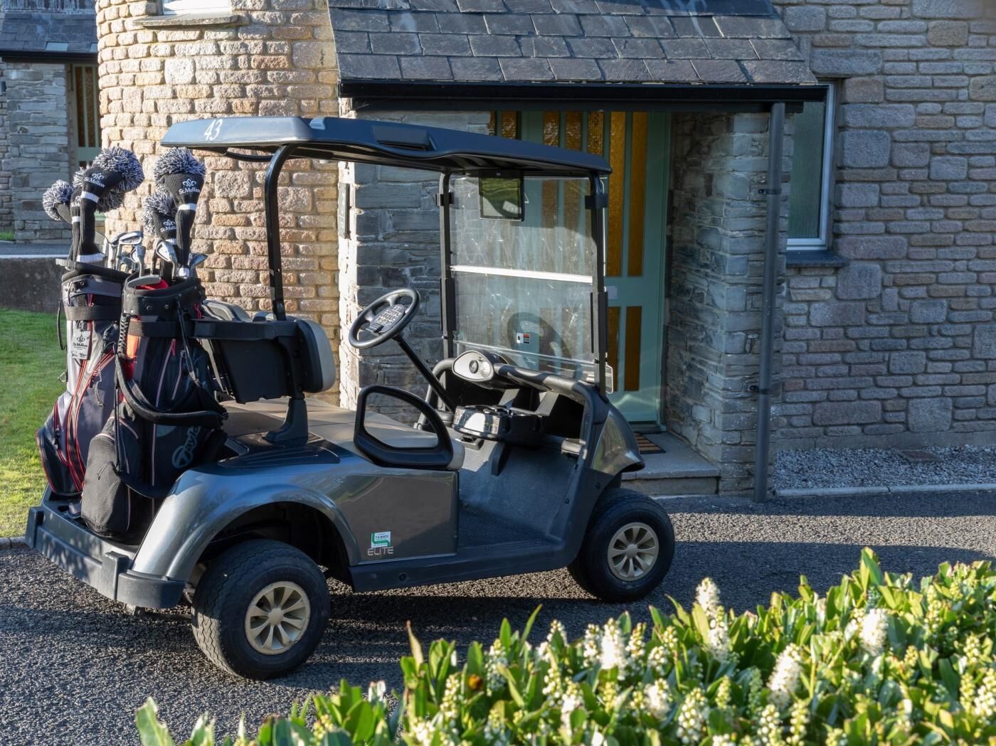 A golf cart parked in front of a stone building with a number '43' sign.