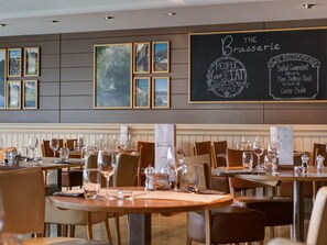 A restaurant interior with tables set for dining, framed pictures on the wall, and a chalkboard menu. - 2 Bed in Saltash (oc-87704) (Saint Mellion)