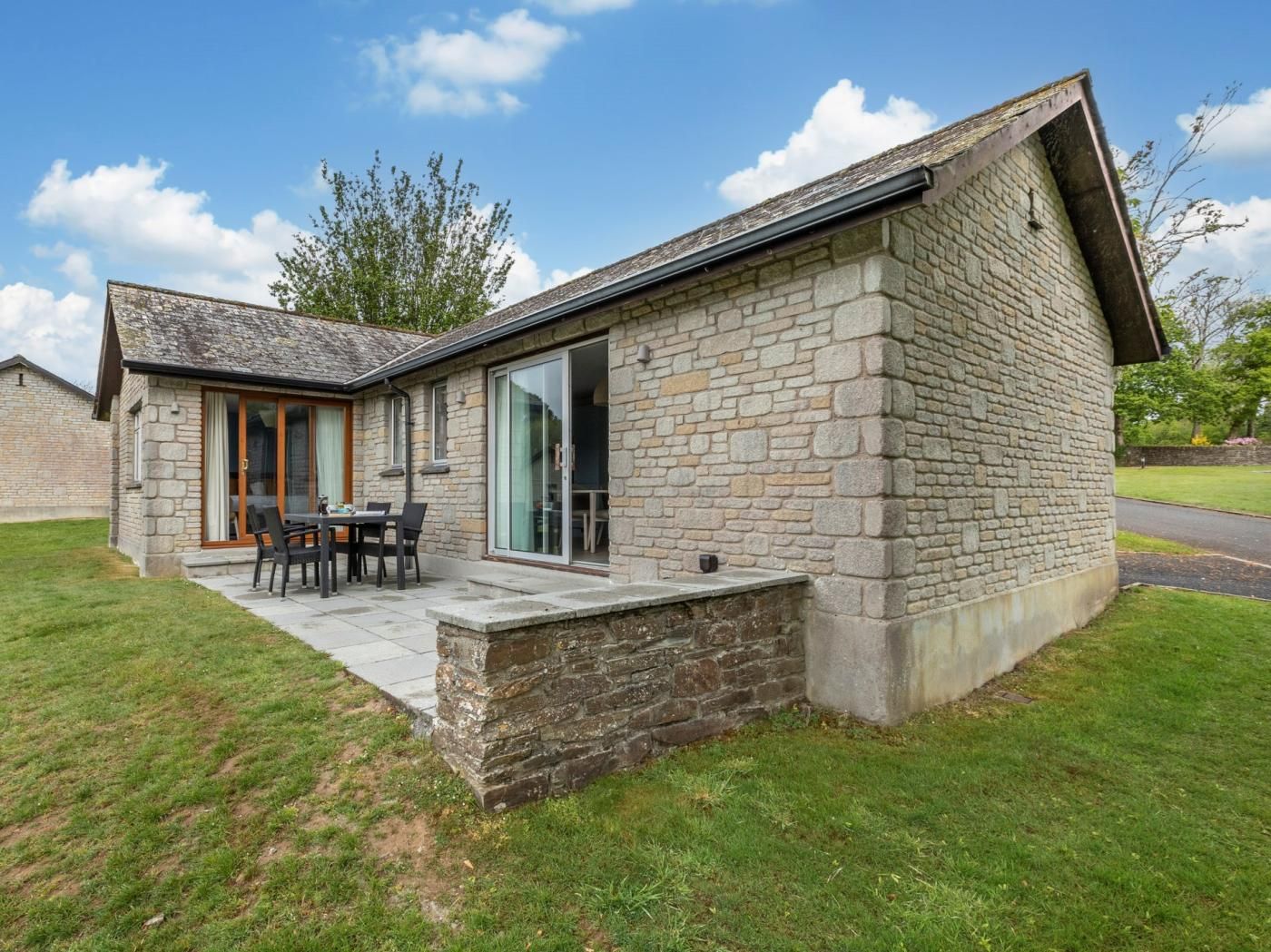 A stone building with a patio and a table with chairs.