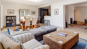 Una sala de estar moderna con tragaluz, un comedor y una cocina.